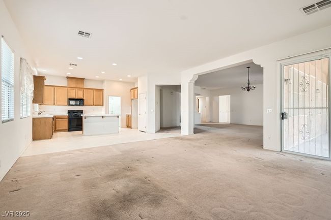 Unfurnished living room featuring visible vents, a notable chandelier, and light colored carpet | Image 14