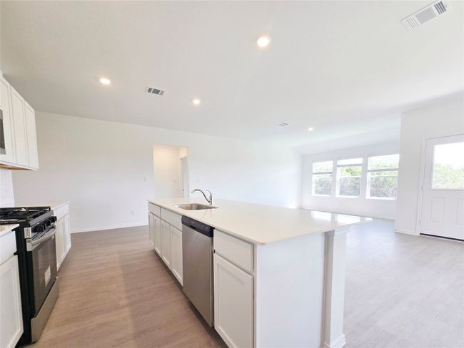 Kitchen with range with gas cooktop, stainless steel dishwasher, a sink, light wood-style floors, and recessed lighting | Image 20