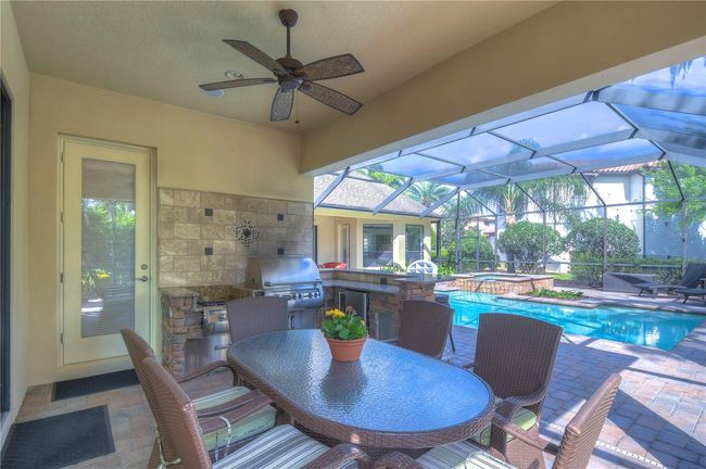 This stunning screened patio with an outdoor kitchen invites endless entertainment, whether you're grilling up a feast or enjoying a peaceful afternoon by the sparkling pool. | Image 31
