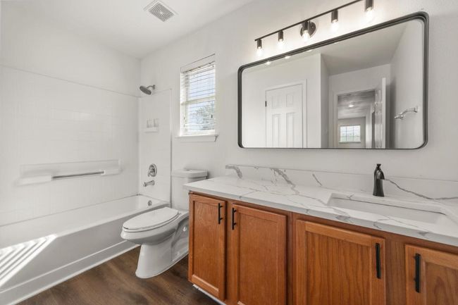 Bathroom with vanity, toilet, visible vents, shower / bathtub combination, and wood finished floors | Image 21