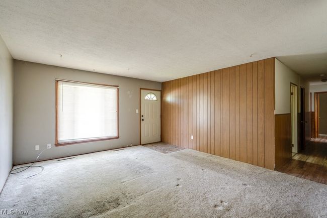 Entrance foyer with carpet floors, wood walls, and a textured ceiling | Image 8