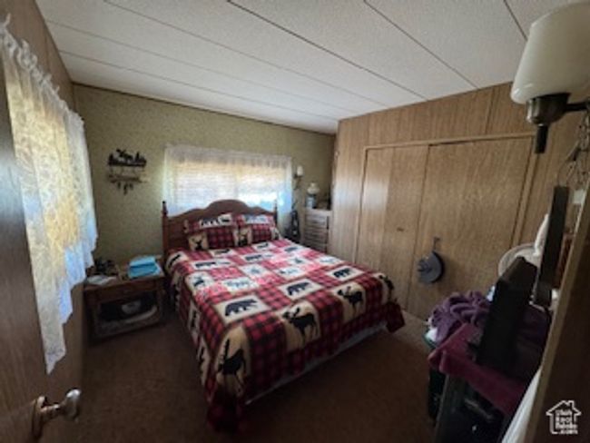 Carpeted bedroom featuring a closet and wooden walls | Image 8