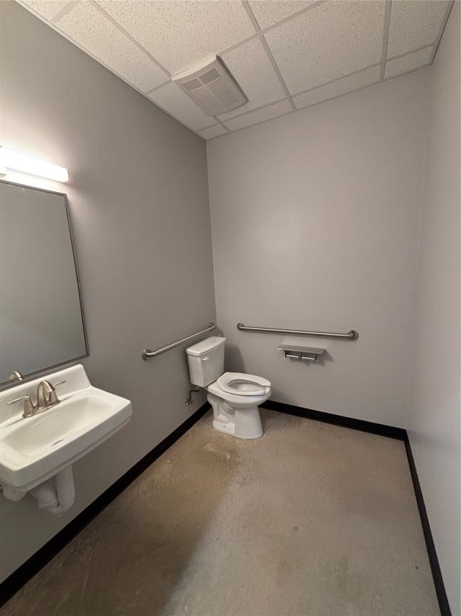 Bathroom with toilet, baseboards, a drop ceiling, a sink, and visible vents | Image 5