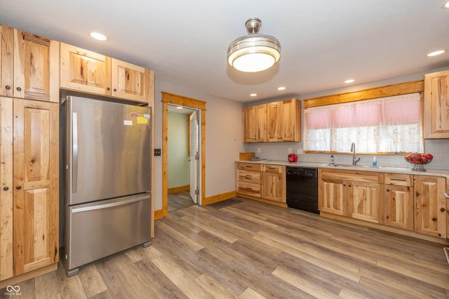 kitchen featuring backsplash, dishwasher, light wood-type flooring, light countertops, and freestanding refrigerator | Image 4