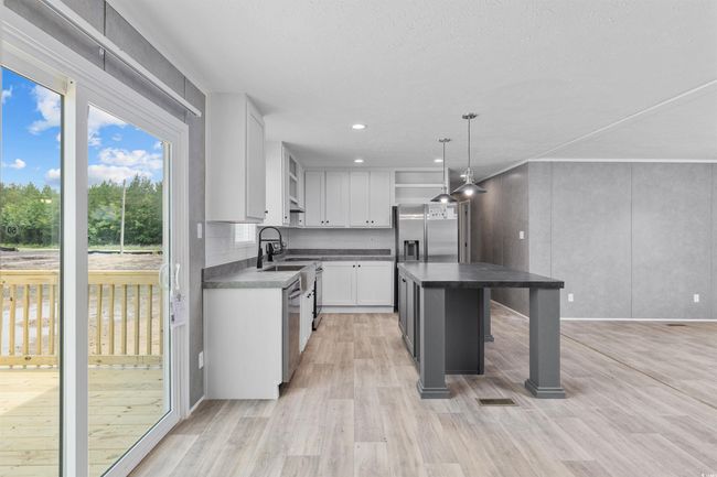 Kitchen with stainless steel appliances, white cabinetry, a center island, light wood-type flooring, and open shelves | Image 20