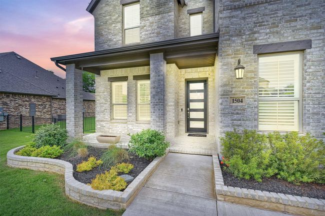 View of exterior entry featuring stone siding, covered porch, and fence | Image 7