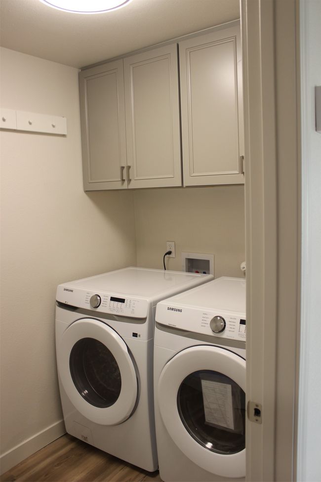 Laundry room with independent washer and dryer, cabinet space, and wood finished floors | Image 18