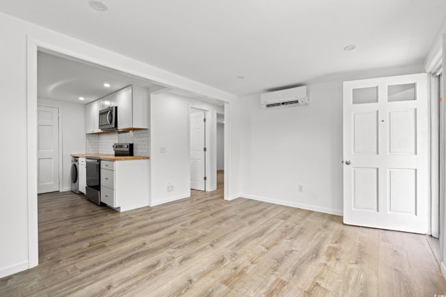 Unfurnished living room with a wall unit AC, light wood-type flooring, washer / clothes dryer, baseboards, and recessed lighting | Image 5