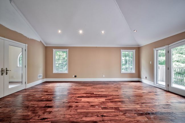 Empty room featuring ornamental molding, french doors, vaulted ceiling, and dark wood-style floors | Image 12