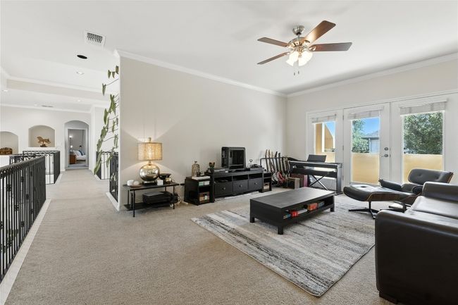 Living area featuring ornamental molding, ceiling fan, arched walkways, light colored carpet, and french doors | Image 32