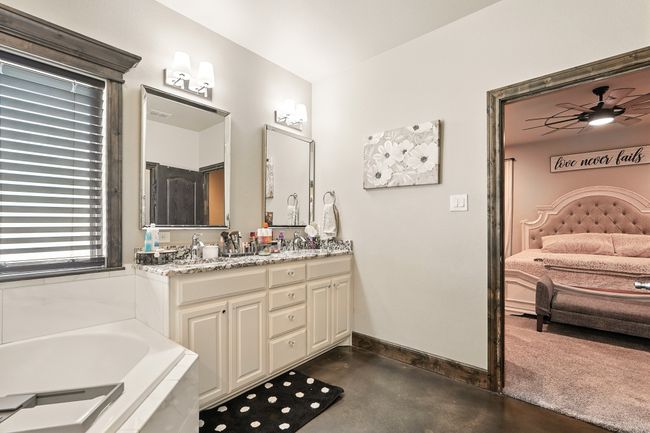 Ensuite bathroom featuring finished concrete floors, double vanity, a garden tub, and a ceiling fan | Image 17