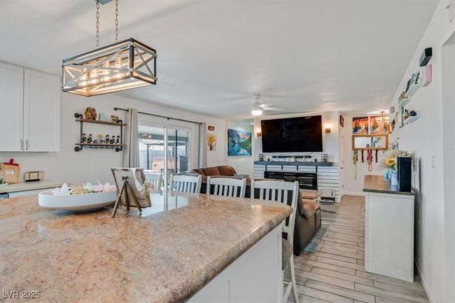 Kitchen featuring ceiling fan, decorative light fixtures, light stone counters, light wood-style floors, and white cabinets | Image 8