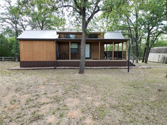 Back of property featuring a metal roof, a storage shed, and covered porch | Image 13