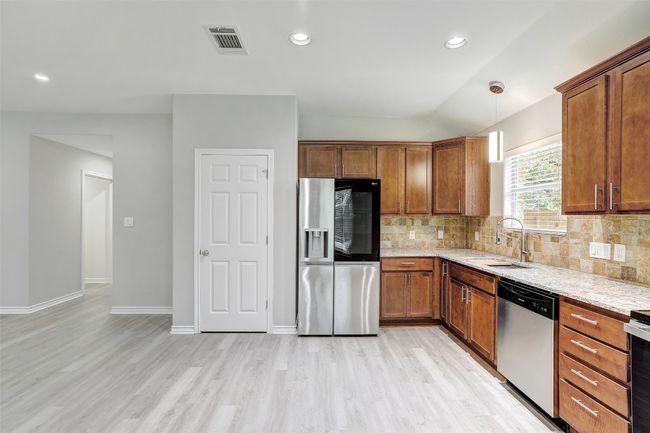 Kitchen with appliances with stainless steel finishes, light wood-style floors, decorative backsplash, light stone countertops | Image 12