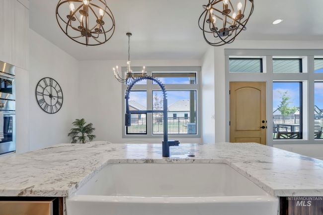 Kitchen with a chandelier, light stone countertops, hanging light fixtures, and lofted ceiling | Image 15
