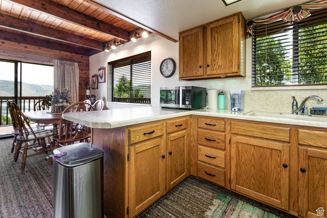 Kitchen with stainless steel microwave, a peninsula, light countertops, plenty of natural light, and a wooden ceiling with exposed beams | Image 20