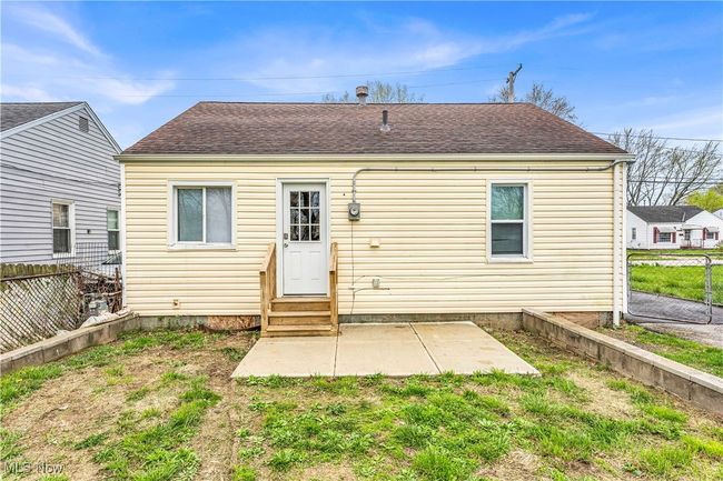 Rear view of property featuring a patio area, entry steps, a shingled roof, and a fenced backyard | Image 21