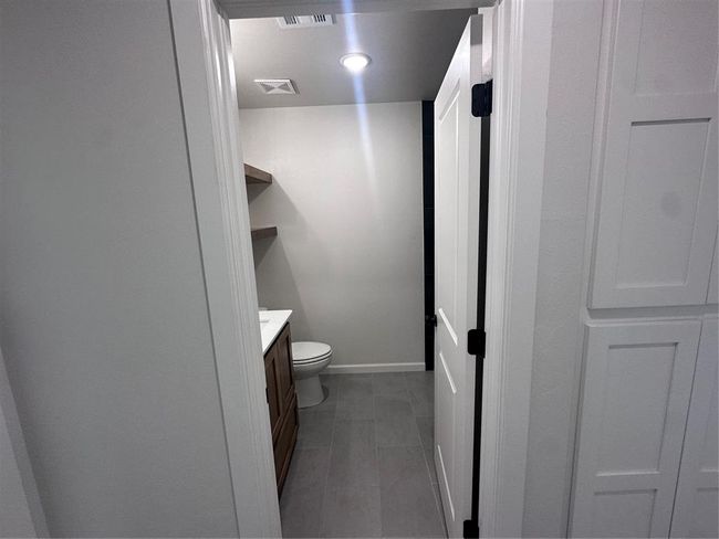 Bathroom with toilet, vanity, baseboards, and visible vents | Image 11