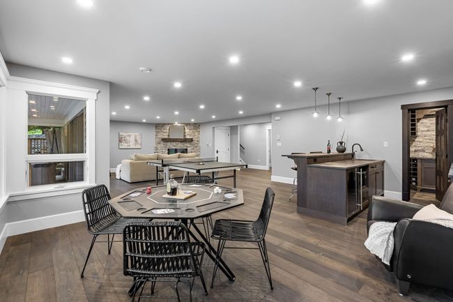 Dining space featuring bar with sink, a large fireplace, baseboards, dark wood-style floors, and recessed lighting | Image 27