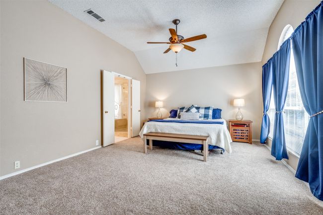 A neutral color scheme, fresh plush carpet installed in 2022, a ceiling fan, and views of the private courtyard-style patio make the spacious, primary suite tucked at the back of this home for privacy and relaxation the perfect retreat. | Image 16