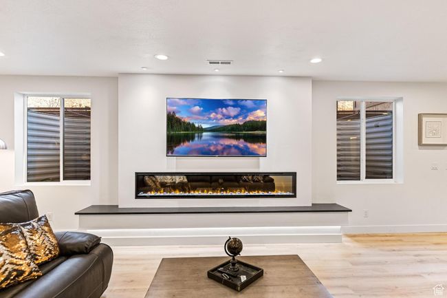 Interior space with visible vents, baseboards, wood finished floors, and a glass covered fireplace | Image 34