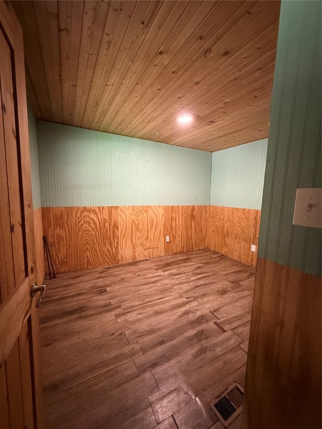 Spare room featuring wooden walls, wood ceiling, and wood finished floors | Image 24