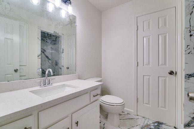 Bathroom featuring a marble finish shower, toilet, marble finish floors, and vanity | Image 23