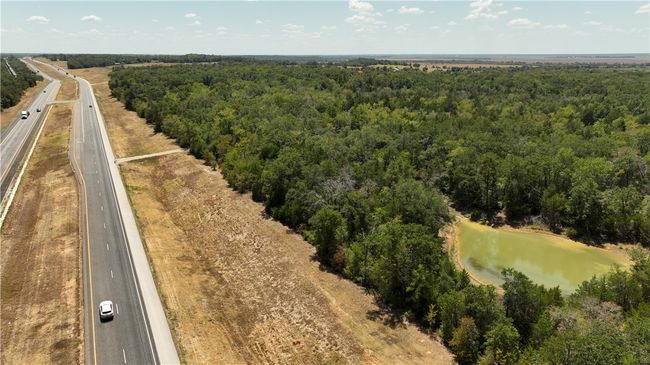 Aerial view of a forest, a nearby body of water, and a major roadway | Image 6