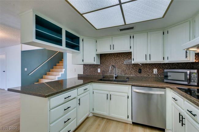 Kitchen with appliances with stainless steel finishes, light wood-style floors, tasteful backsplash, a peninsula, and white cabinetry | Image 26