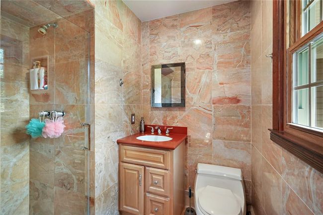Bathroom featuring vanity, tile walls, a tile shower, and toilet | Image 17