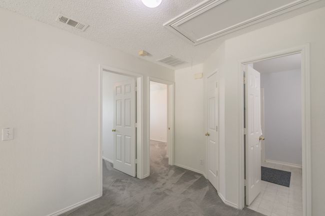 Hall with attic access, a textured ceiling, baseboards, visible vents, and carpet floors | Image 13