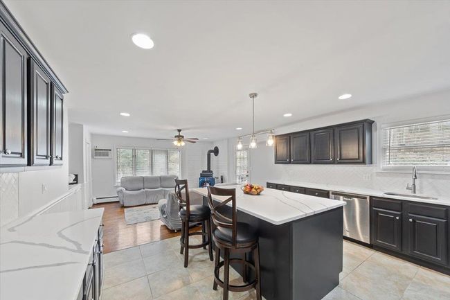 Kitchen featuring dishwasher, a sink, open floor plan, a wood stove, and a kitchen breakfast bar | Image 31