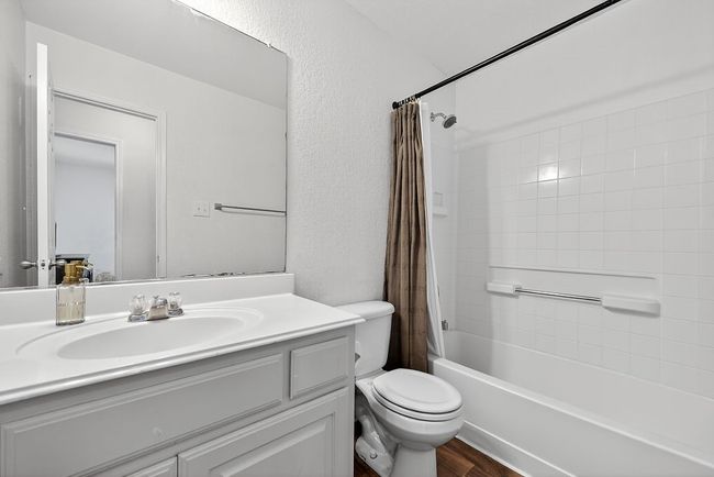 Bathroom featuring vanity, shower / bath combination with curtain, and wood finished floors | Image 27
