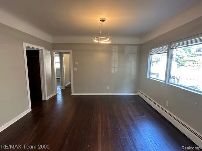 Unfurnished dining area featuring a baseboard heating unit and dark wood-type flooring | Image 11