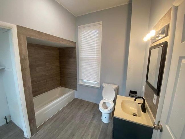 Bathroom with wood-type flooring, a bathing tub, vanity, and toilet | Image 4