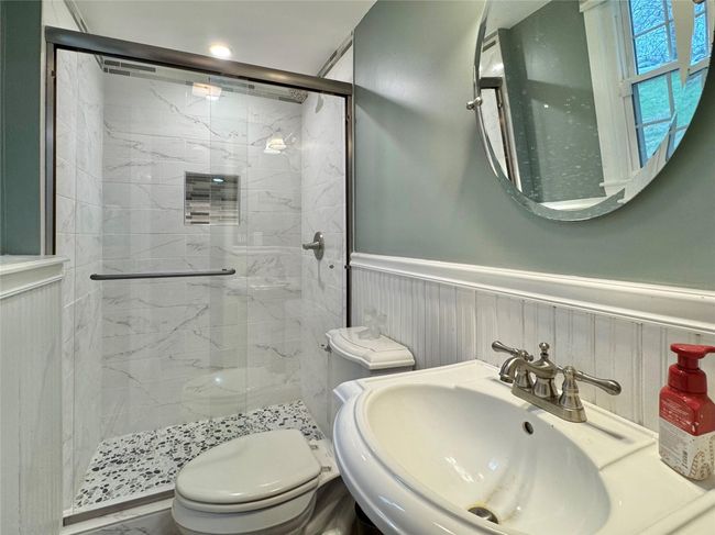 Bathroom with a sink, a wainscoted wall, a stall shower, and toilet | Image 23