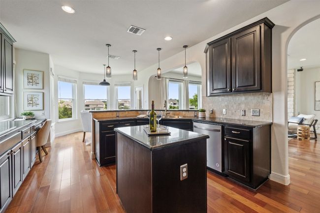 Kitchen featuring a peninsula, a kitchen island, decorative light fixtures, tasteful backsplash, and dishwasher | Image 18