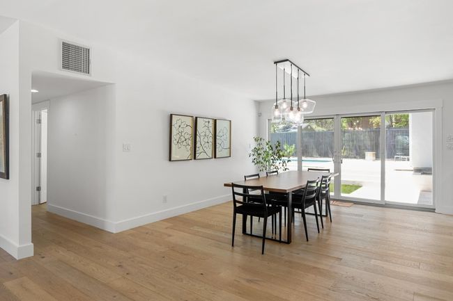 Dining area with light wood-style floors, baseboards, visible vents, and a notable chandelier | Image 5