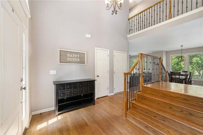 Stairs with a chandelier, wood finished floors, baseboards, and a high ceiling | Image 5
