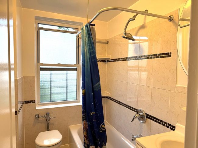 Full bathroom with tile walls, shower / bathtub combination with curtain, and a wainscoted wall | Image 18