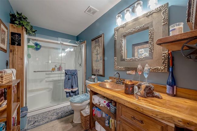 Thoughtfully designed with a wide vanity and framed mirror, this bathroom’s muted blue palette and enclosed shower area offer both charm and utility. | Image 28