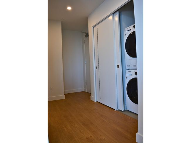 Laundry room featuring baseboards, recessed lighting, wood finished floors, stacked washer / drying machine, and laundry area | Image 9