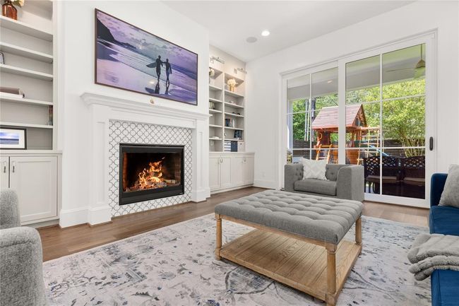 Gas fireplace, built-in entertainment center w/ shelving, cabinets, & lighting; Sliding doors to outdoor kitchen. | Image 16