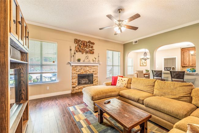 Living room with arched walkways, a textured ceiling, a fireplace, dark wood finished floors, and crown molding | Image 15