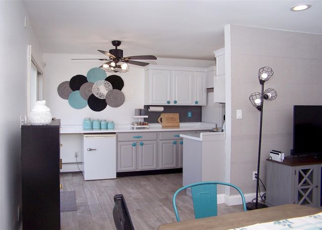 Kitchen with light hardwood / wood-style flooring, ceiling fan, a baseboard radiator, and white cabinets | Image 6