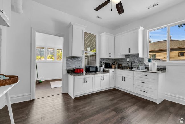 Kitchen featuring a ceiling fan, tasteful backsplash, dark wood-style floors, and dark stone counters | Image 7