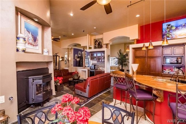 Living area featuring arched walkways, a ceiling fan, a wood stove, recessed lighting, and wine cooler | Image 41