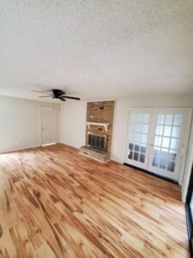 Unfurnished living room featuring a textured ceiling, wood finished floors, a fireplace, and ceiling fan | Image 27