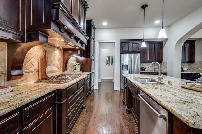 The upgraded vent hood serves as the centerpiece of this kitchen, creating a grand focal point, while the elegant backsplash adds a sophisticated touch. | Image 12