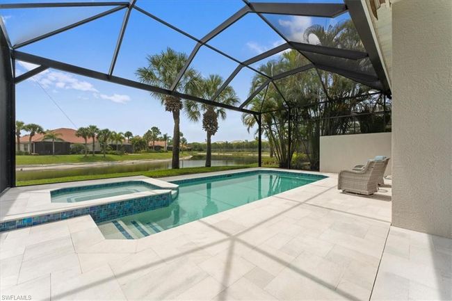 View of swimming pool with a patio area, a water view, a pool with connected hot tub, and glass enclosure | Image 14